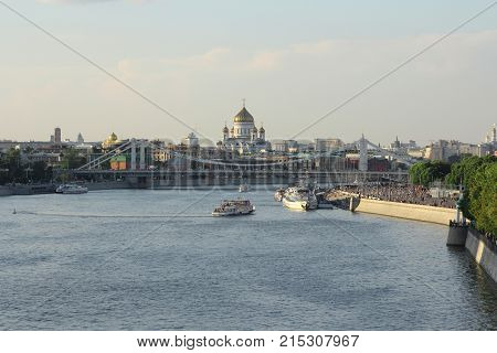 Moskva river with river buses from Novoandreevskiy Bridge. Krymsky bridge and Cathedral of Christ the Savior on the horizon in Moscow Russia.
