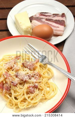 spaghetti carbonara into plate, with egg, chees and bacon