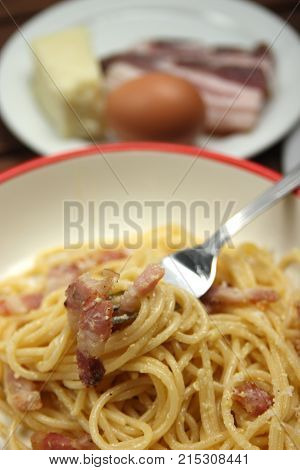 spaghetti carbonara into plate, with egg, chees and bacon