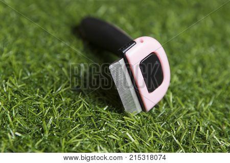 Black with pink furminators for cats on the background of artificial grass