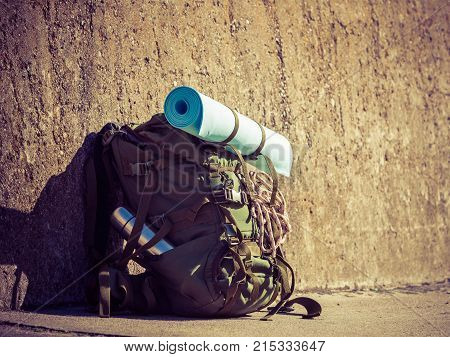 Hiking backpack camping and mountain exploring tourist equipment outdoor on grunge wall. Adventure summer tourism active lifestyle