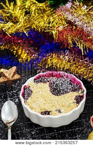 Homemade delicious crumble with berries in portioned individual ramekin. Christmas concept. Selective focus. Copy space.