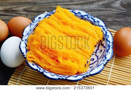 Golden egg strip is Thai desserts made from eggs with Thai style bowl on wooden background