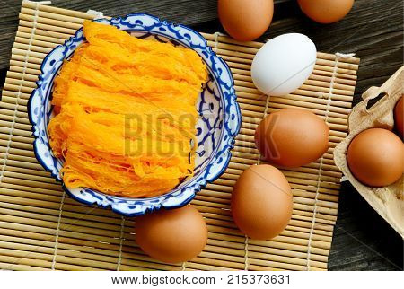 Golden egg strip is Thai desserts made from eggs with Thai style bowl on wooden background