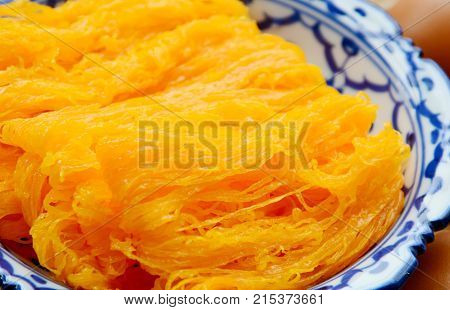 Golden egg strip is Thai desserts made from eggs with Thai style bowl on wooden background