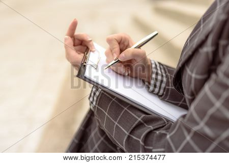 Woman writes something on paper starts to write a letter a document signs papers using a pen. Person sign document write on paper using pen.