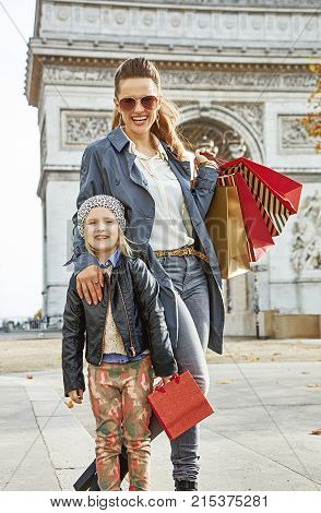 Stylish autumn in Paris. happy young mother and child with shopping bags near Arc de Triomphe in Paris France
