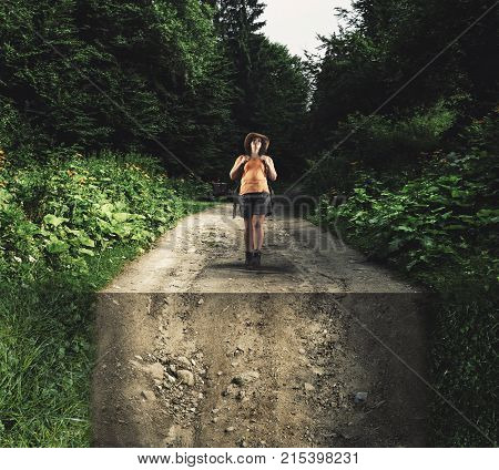 Young girl walking in forest on a road bent down.