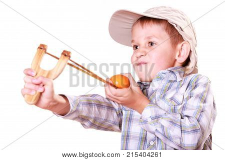 Nature and free time prankster little boy. Child have fun with wooden sling shot and fruit aim mandarine.
