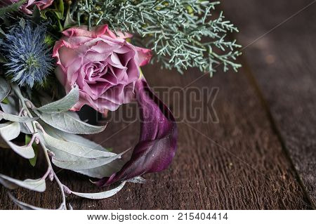 femininity, nature, floral design concept. close up of extremelly beautiful rose in delicate pink colour that is surrounded with leaves and small conifer branches, thistles and lilies