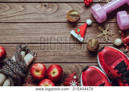 Fitness healthy and active lifestyles love concept dumbbells sport shoes skipping rope or jump rope and apples with Christmas decoration items on wood background. Exercise Fitness and Working Out Merry Christmas and Happy new year concept.