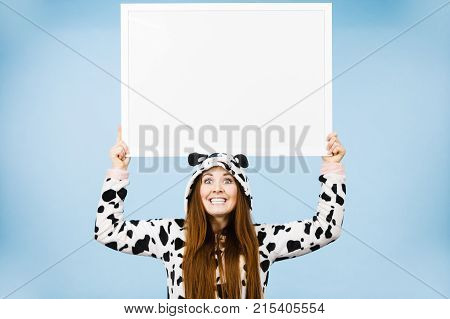 Smiling teenage girl in funny nightclothes pajamas cartoon style with blank empty banner board. Advertisement copyspace.