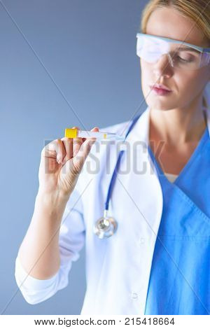 Female medical or research scientist or doctor using looking at a test tube of clear solution in a lab or laboratory