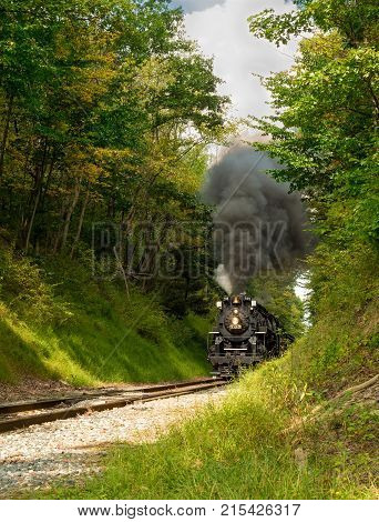 PENINSULA OH - SEPTEMBER 17 2917: The NKP-765 one of the largest steam locomotives still in existence approaches with a full billow of smoke from a narrow pass through woods south of Cleveland.