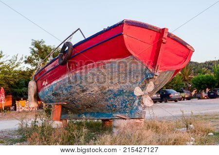 Overgrown in weed old wooden fishing boat dry docked withdrawn to the beach.