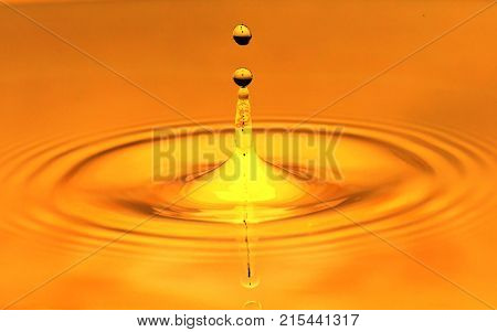 a drop of water falls in a golden water. macro .