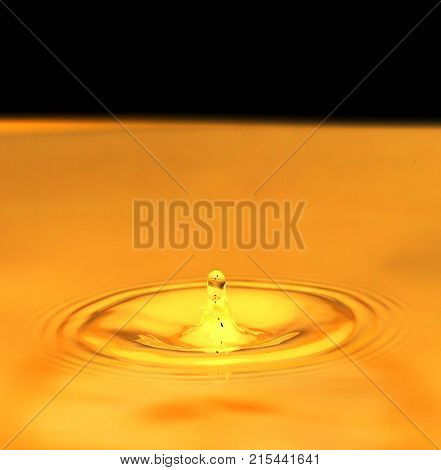 a drop of water falls in a golden water. macro .