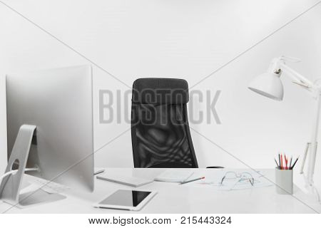 Office light interior of work place table with modern computer and fashionable monitor keyboard mouse documents lamp tablet pencils glasses and chair on white background.