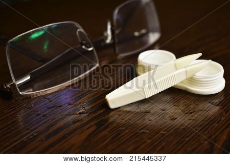 glasses tweezers lens case and solution on the table
