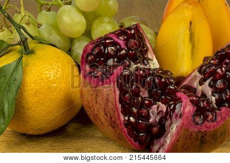 fruit ripe red pomegranate white grapes orange mandarin with green leaves and persimmon