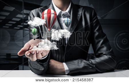 Closeup of business woman in suit presenting flying aerostate among clouds in her palm with dark office view on background. 3D rendering.