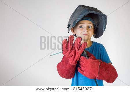 Happy little kid in welder mask and welding equipment. Welding equipment welding mask protective leather gloves welding electrodes. Fun concept. Child dreaming of future profession. Career choice.