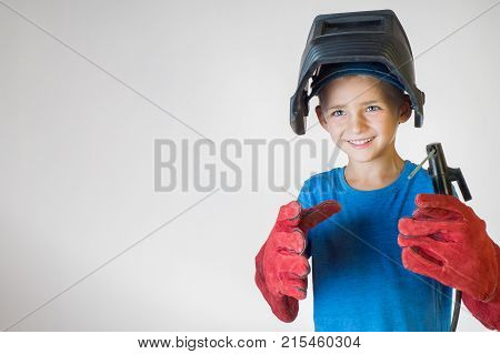 Happy little kid in welder mask and welding equipment. Welding equipment welding mask protective leather gloves welding electrodes. Fun concept. Child dreaming of future profession. Career choice.