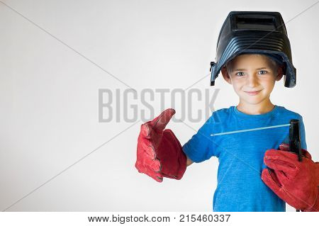 Happy little kid in welder mask and welding equipment. Welding equipment welding mask protective leather gloves welding electrodes. Fun concept. Child dreaming of future profession. Career choice.