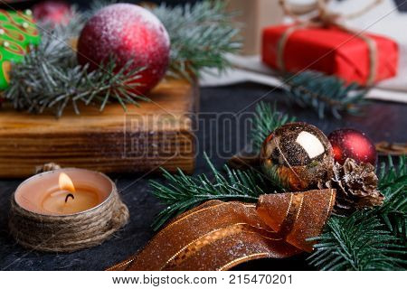 Close-up on a wooden board is a toy red ball, sprig of spruce, a candle burns, a New Year's concept, a new year, Christmas.