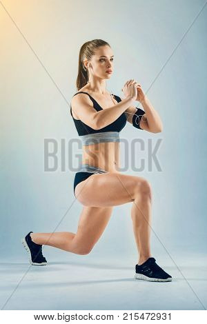 Say no to a passive lifestyle. Muscular female athlete listening to the motivating music and focusing on her training session while doing a lunging exercise alone.