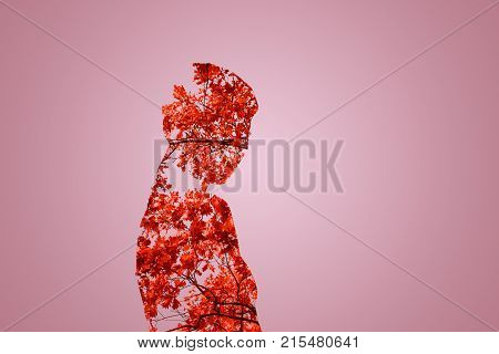 Mysterious lady. Waist up shadowgraph of a girl looking into the camera while standing against the leaves background.