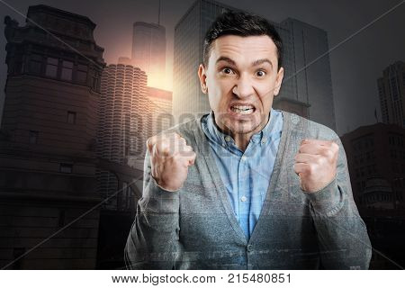Stop doing that. Furious young man cannot keep his emotions inside and showing his fists after having a nervous breakdown.