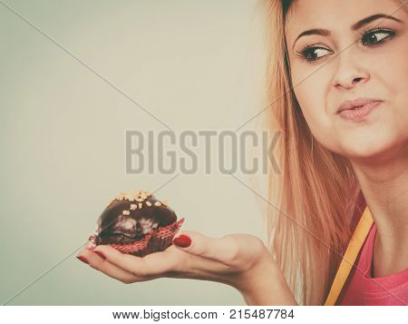 Diet sweets food concept. Woman holding delicious chocolate cupcake with peanut frosting about to take bite