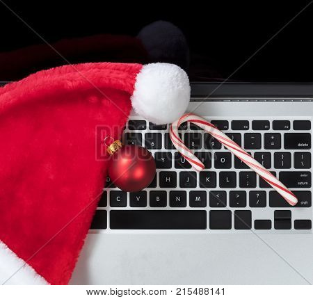 Santa Claus hat and candy cane on top computer keyboard during Christmas holiday shopping season