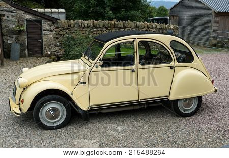 OSWESTRY, UK - SEPTEMBER 24, 2016: Restored cream colored Citroen 2CV6 french car in driveway of old house