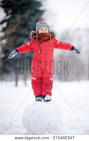 Little Boy In Red Winter Clothes Having Fun With Snowball