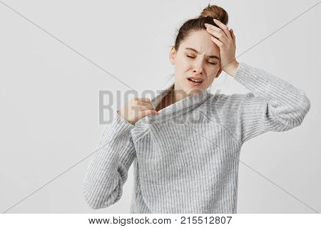 Exhausted girl holding her head with closed eyes being hot. Female office assistant suffering from temperature and fever she needs fresh air. Health concept