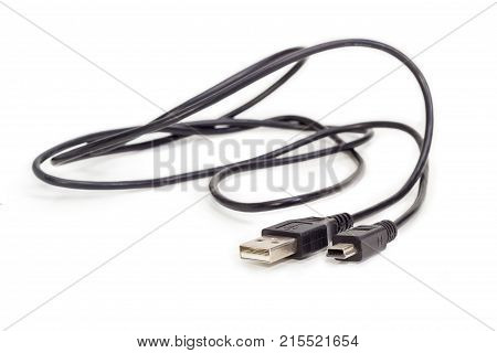 Plugs USB and mini-USB on ends of black cable closeup at shallow depth of field on a white background