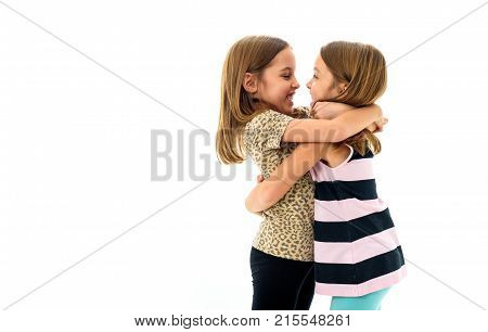 Identical Twin Girls Are Looking At Each Other And Smiling.