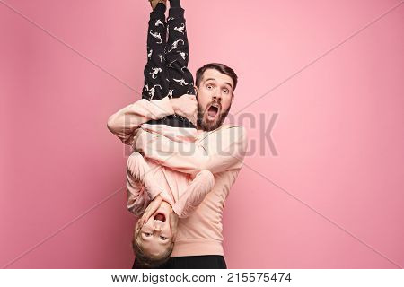 The surprised and cheerful father playing with daughter at pink studio