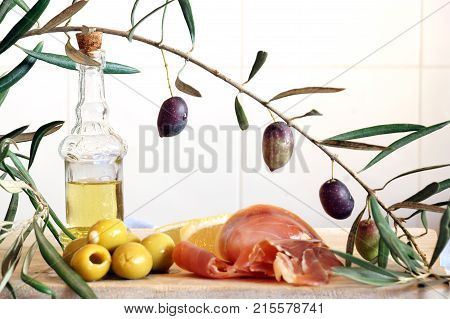 A Bottle With Olive Oil, An Olive Branch And A Light Breakfast From Stuffed Olives And A Jamon.