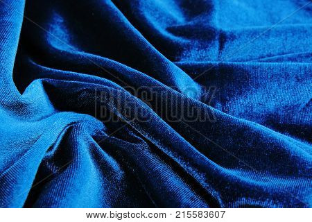 Silk dress material cloth texture pattern. Tailoring stitching concept. Shiny beautiful fashion fabric. Shiny clothing material sample.Creased fabric. Velvet blue.