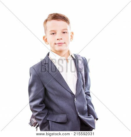 Serious young male student of primary school isolated on white background. Calm and confident schoolboy in suit with backpack on his shoulder