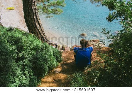 Man with sitting on top of hill and enjoying on view the bay of Kabak beach and sea landscape. Hiking travel to Turkey, lycian way