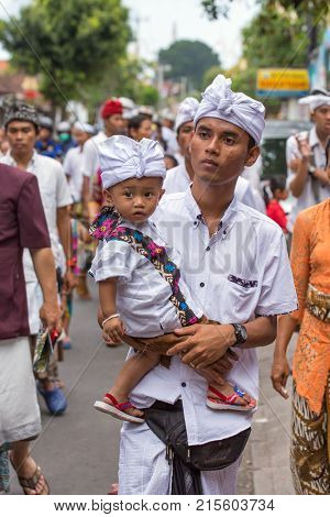 Bali, Indonesia - September 17, 2016: Unidentified balinese man with a child carry offerings for gods during Galungan and Kuningan in Ubud, Bali