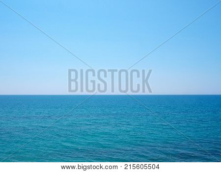 Blue ocean. A clear sunny day. Small waves. A direct horizon and an immense distance. Clear blue sky. There is not a single cloud.