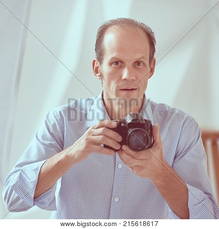 Young professional photographer taking photos in modern studio, image with vintage toning