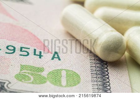 White capsules of glucosamine chondroitin healthy supplement pills on dollar banknote macro image.