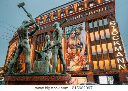 Helsinki, Finland - December 8, 2016: Night View Of Famous Sculpture Group Three Smiths Statue Near Stockmann Shop In Evening Or Night Illumination