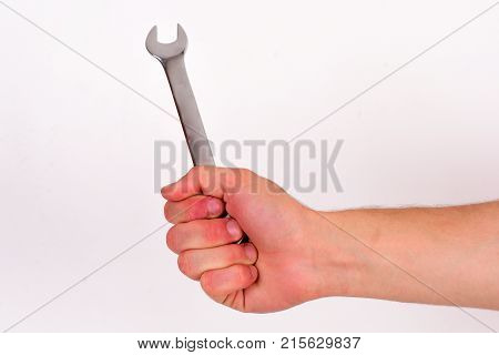 Repairer or mechanic hand holds spanner instrument. Service and engineering concept. Wrench tool in male hand isolated on white background. Spanner equipment made of metal.